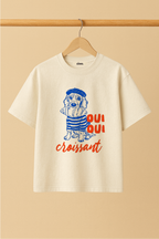 Ziaa's white t-shirt with a dog and crossiant graphic and text "Oui Oui Crossiant"